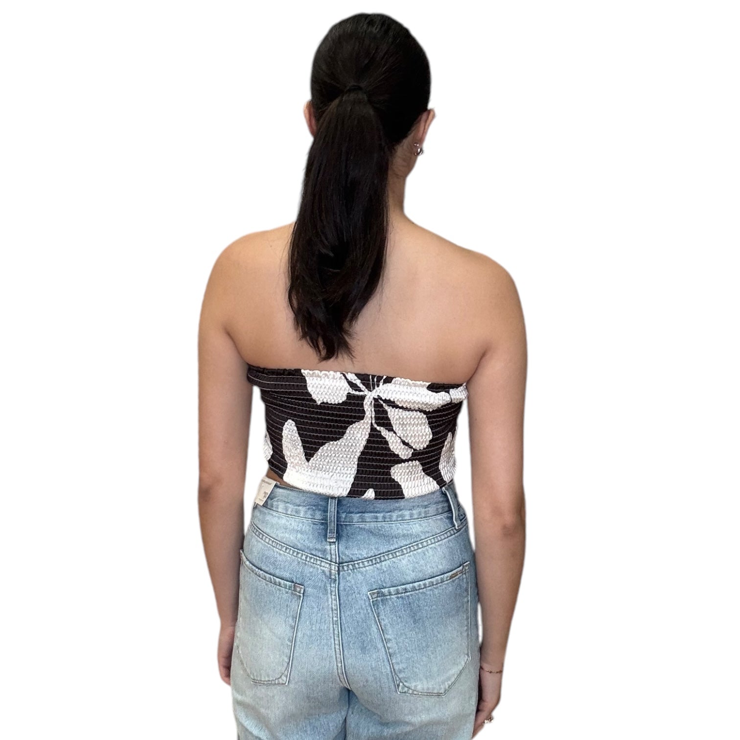 Back view of a model wearing a strapless satin scarf top in chocolate, paired with high-waisted denim shorts.