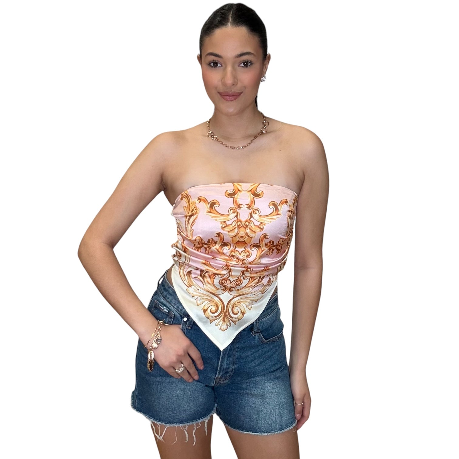 Model wearing a strapless satin scarf top in pink with elegant design, paired with denim shorts.