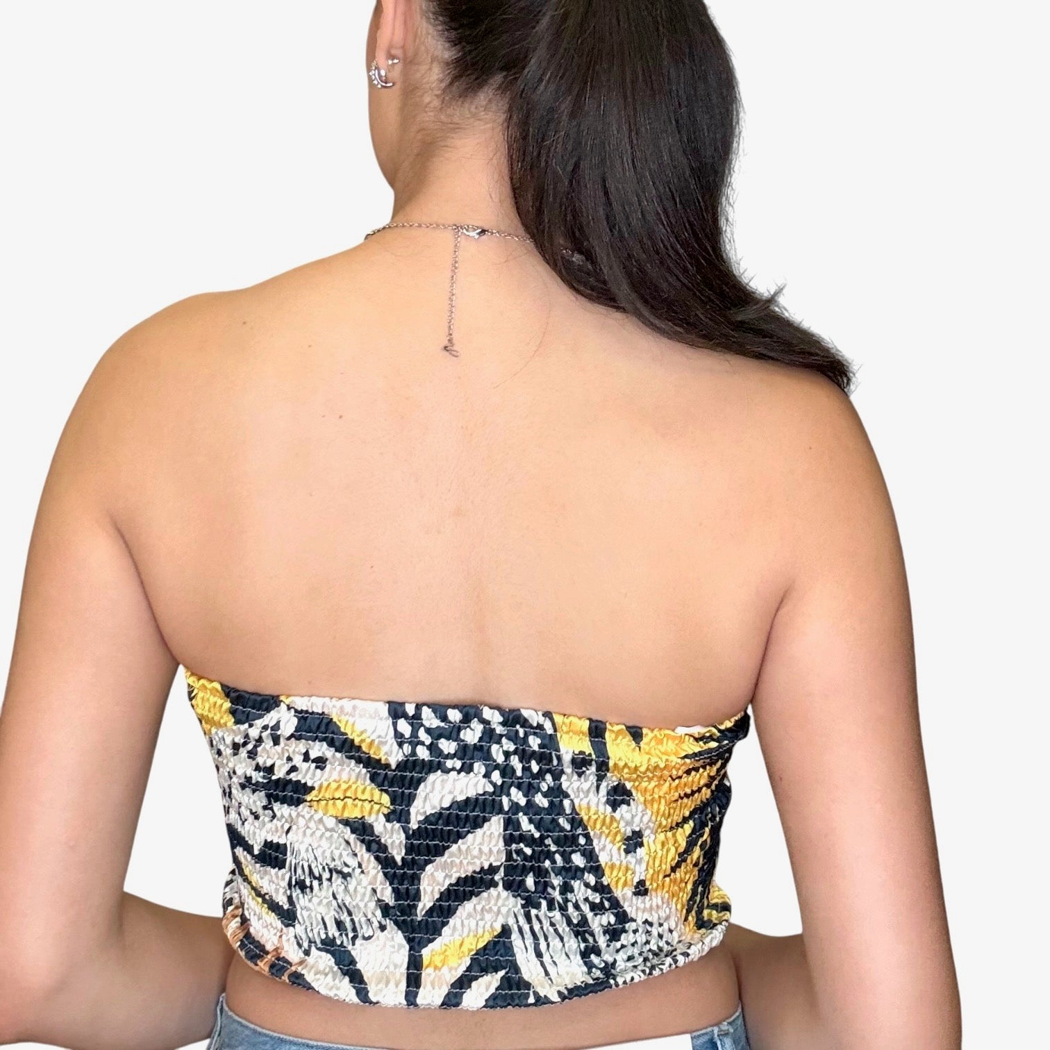 Back view of a woman wearing a strapless satin scarf top with a colorful, patterned design, showcasing a chic summer style.