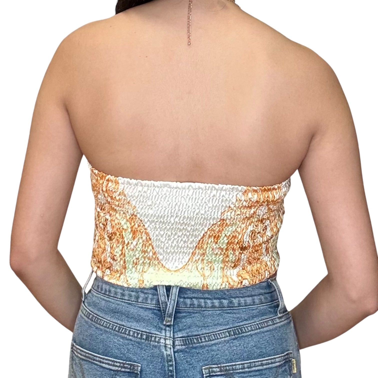 Back view of a strapless satin scarf top in lemon with smocked detailing, paired with high-rise denim shorts.