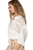 Model wearing a Vintage Lace Cropped Jacket Top in off white, featuring a collared neckline and ruffled hem.