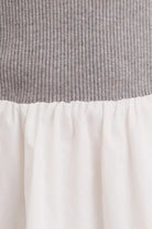 Close-up of a grey ribbed sweater top and white flared mini dress bottom, showcasing the textured knit and soft fabric.